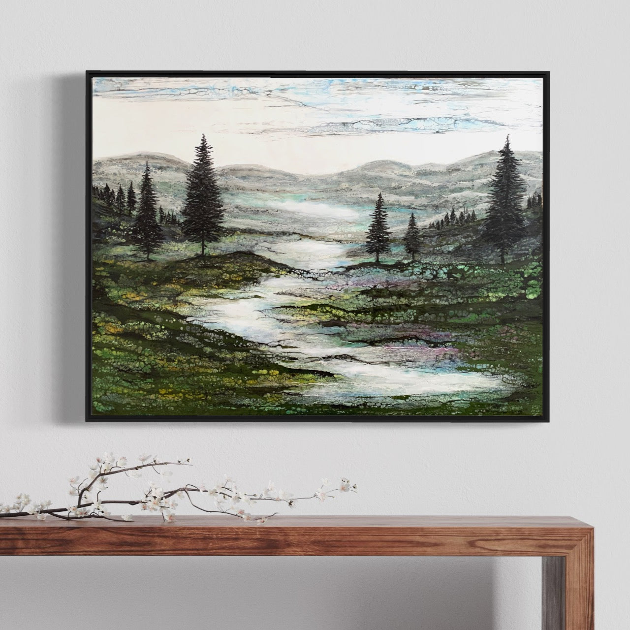 Gerahmtes Enkaustikbild an der Wand über einem Tisch zeigt eine grüne Landschaft mit einem Fluss und Bäumen