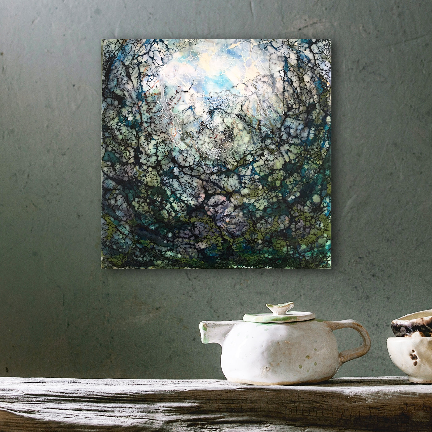 Abstraktes Enkaustik Kunstwerk in dunklen Farben hängt dekorativ über einem Esstisch