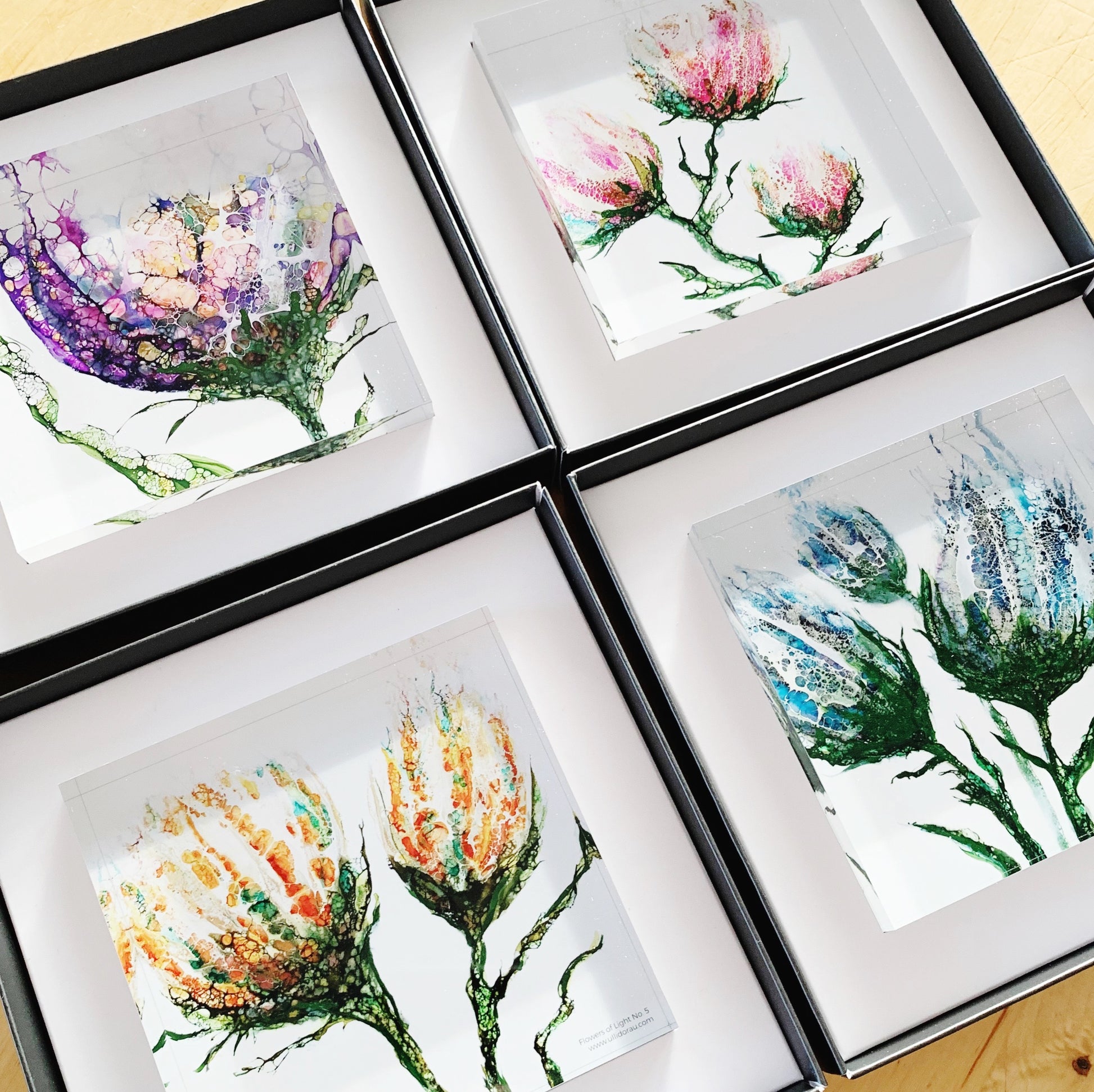 Vier Kunstdrucke in Acrylglas zeigen unterschiedliche Blumenmotive. Acrylglasblöcke sind In Geschenkboxen verpackt